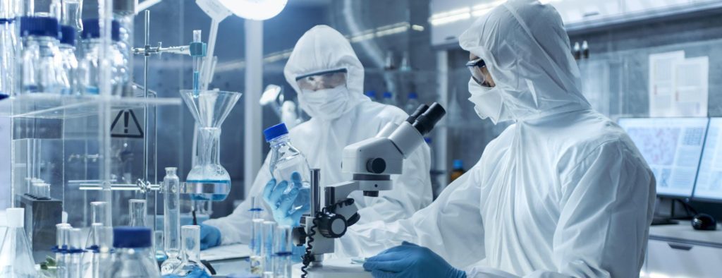 2 workers in clean room with coveralls, googles and gloves.