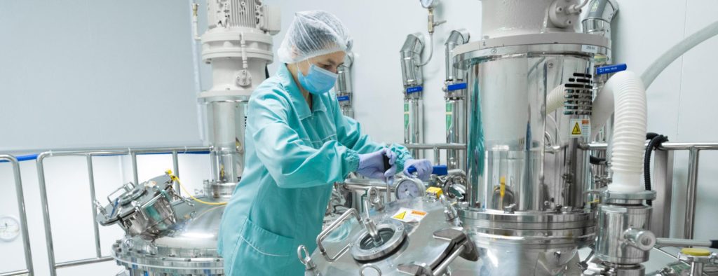 worker with gloves, coverall, facemask working on equipment