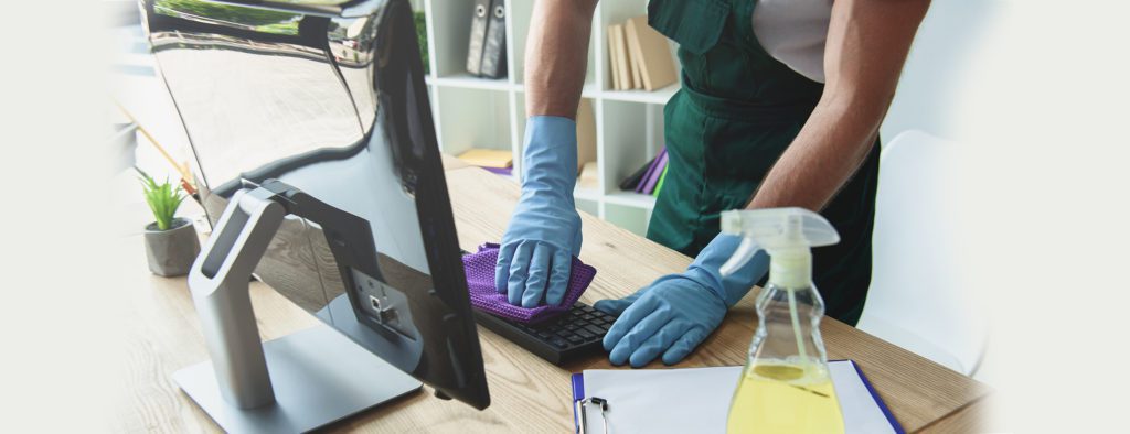 Person Cleaning covid-19 on Computer Keyboard with Towel and Spray While Wearing Gloves