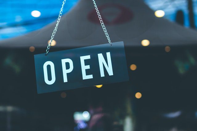 Open sign hanging behind glass